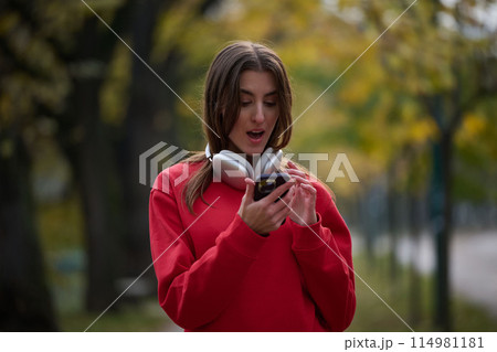 Sporty woman checks smartphone before doing some exercises listens music from a playlist 114981181