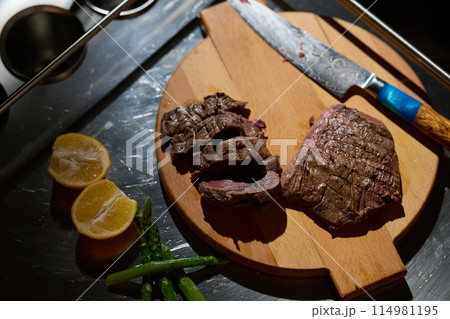 Close-up shot, a professional chef expertly prepares a delicious steak using modern cooking techniques, showcasing culinary excellence and precision in the art of gourmet cuisine 114981195