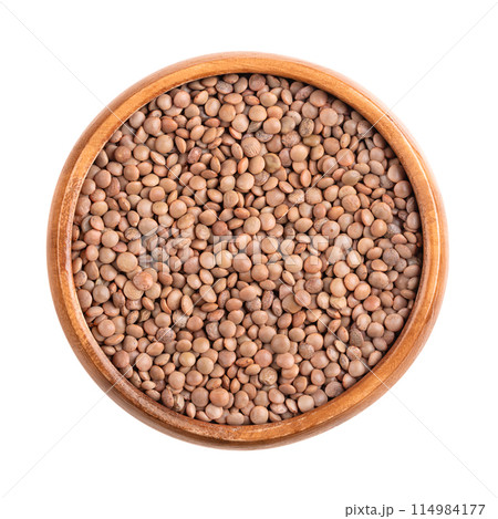 Chateau lentils in a wooden bowl. French specialty and a variety of light brown lentils. Dried fruits of Lens culinaris, an edible legume with lens-shaped seeds. Suitable for salads and as side dish. 114984177
