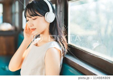 電車で音楽を聴く女性 114984809