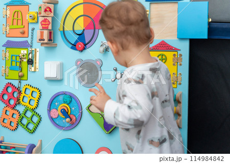 A child in front of a large board with interest selects elements for the game 114984842