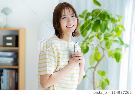 部屋でスマホを操作する若い女性 114987269
