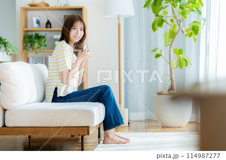 部屋でスマホを操作する若い女性 部屋でスマホを操作する若い女性 114987277