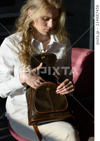 beautiful curly blond hair woman posing with a leather backpack beautiful curly blond hair woman posing with a leather backpack 114987456