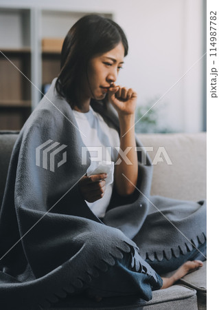 Upset woman frustrated by problem with work or relationships, sitting on couch, embracing knees, covered face in hand, feeling despair and anxiety, loneliness, having psychological trouble 114987782