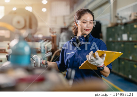 professional engineer worker with safety eyes protection focus working in metal lathe milling machine heavy industry factory. 114988121