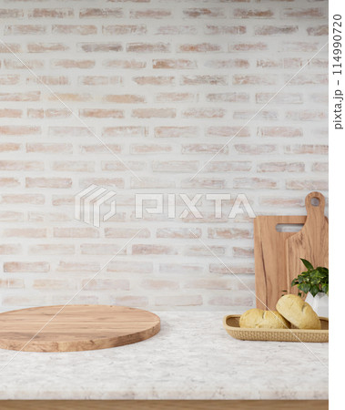 A showcasing space on a round wooden board on a marble table against the brick wall in a kitchen. 114990720