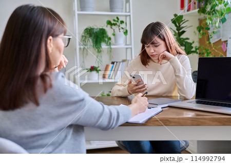 Sad teenage girl talking to psychotherapist at therapy session in office Sad teenage girl talking to psychotherapist at therapy session in office 114992794