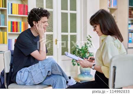 Psychologist working with young male college student in educational office Psychologist working with young male college student in educational office 114992833