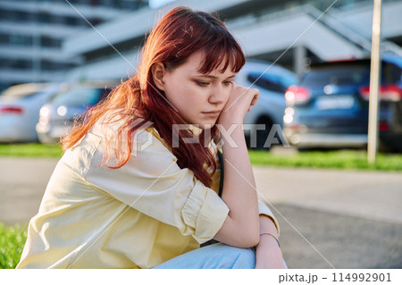 Upset sad unhappy young female sitting outdoor on steps 114992901