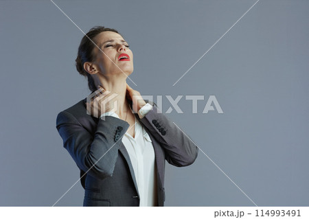 tired elegant woman employee having neckpain isolated on grey tired elegant woman employee having neckpain isolated on grey 114993491