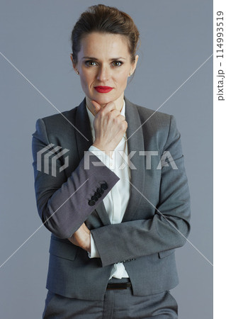 pensive modern business woman in gray suit isolated on grey 114993519