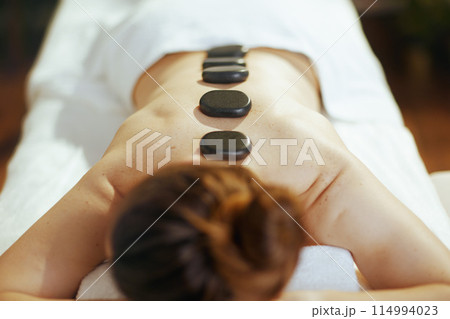 Female having hot stone massage and laying on massage table 114994023
