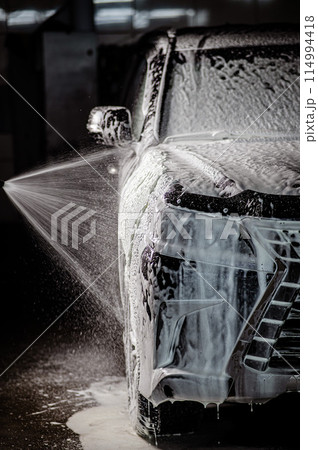 Man applying foam to black car in car wash. Vertical photo. Man applying foam to black car in car wash. Vertical photo. 114994418