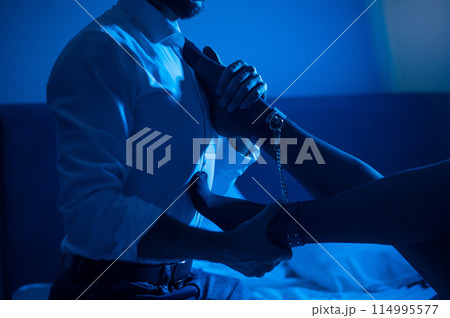A man holds a woman by the ankles. BDSM concept. A man holds a woman by the ankles. BDSM concept. 114995577