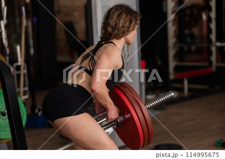 Middle-aged woman doing abdominal rows on a machine in the gym. Middle-aged woman doing abdominal rows on a machine in the gym. 114995675