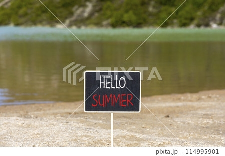 Hello summer symbol. Concept words Hello summer on beautiful yellow blackboard. Beautiful mountain lake sand beach background. Business lifestyle Hello summer concept. Copy space. 114995901