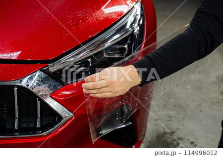 The process of applying protective vinyl film to car headlights in detailing. The process of applying protective vinyl film to car headlights in detailing. 114996012