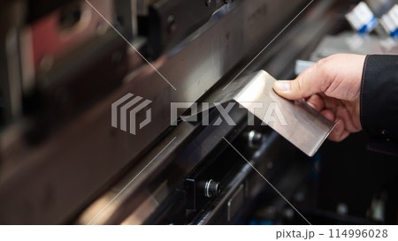 A master bends metal sheets on a machine. Hydraulic Press.  114996028