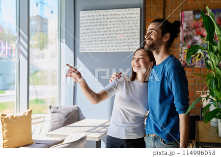 Young happy couple hugging together looking out the window 114996058