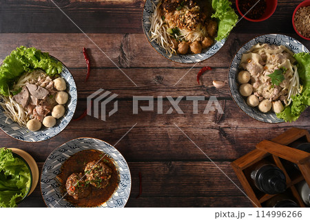 Tasty spicy Thai noodles, scalded meatball and condiment set for seasoning on wooden table 114996266