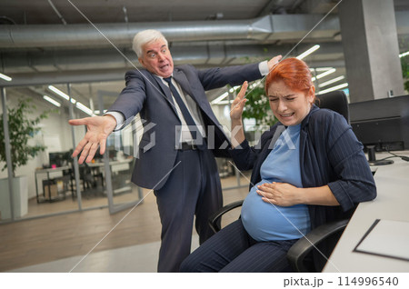 Boss swears at pregnant subordinate woman in office.  114996540