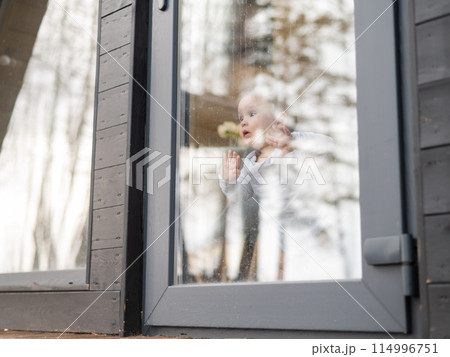 Baby boy standing by the patio window.  114996751