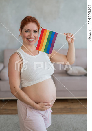 Happy pregnant woman holding a rainbow flag. Happy pregnant woman holding a rainbow flag. 114996804