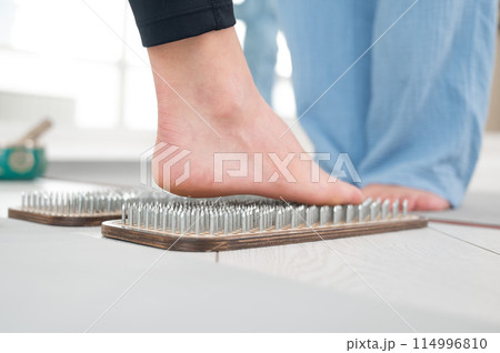 Caucasian woman stands on sadhu boards with therapist support. 114996810