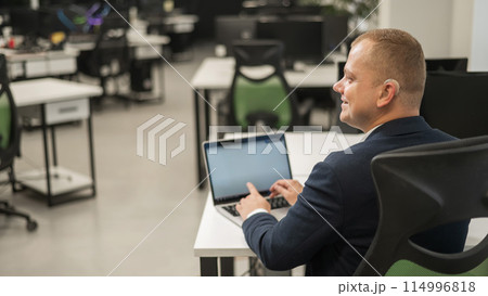 Caucasian deaf man typing on laptop in office.  114996818