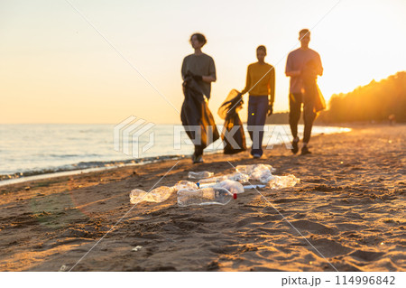 Earth day. Volunteers activists team collects garbage cleaning of beach coastal zone. Woman mans with trash in garbage bag on ocean shore. Environmental conservation coastal zone cleaning Earth day. Volunteers activists team collects garbage cleaning of beach coastal zone. Woman mans with trash in garbage bag on ocean shore. Environmental conservation coastal zone cleaning 114996842