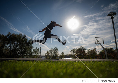 Caucasian man jumping with high hip raise outdoors. Caucasian man jumping with high hip raise outdoors. 114997035