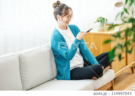 お家のソファーでスマホを見る女性 114997043