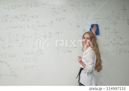 Caucasian woman erasing formulas from white board.  114997132