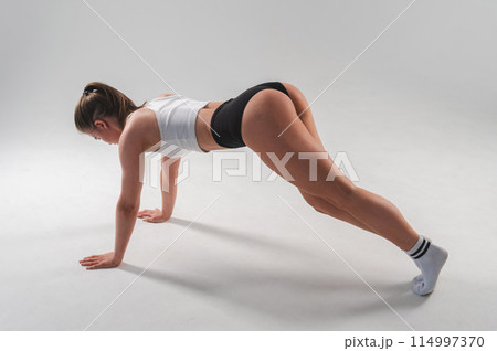 Athletic woman in shorts doing plank on white background. Athletic woman in shorts doing plank on white background. 114997370