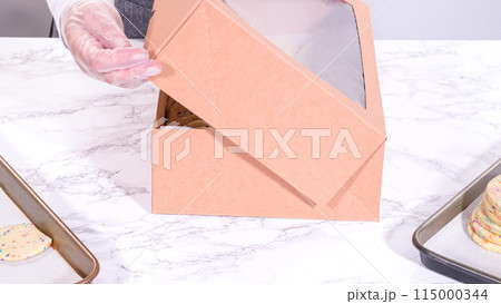 The sugar cookies, filled with sprinkles mixed into the dough, are carefully arranged with meticulous precision into a rustic brown paper box. 115000344