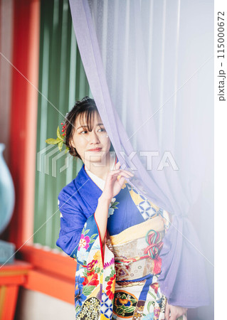 カラフルな布の隙間から除く和装の若い女性 115000672