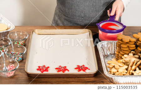 Vivid red star-shaped cookies, generously iced and speckled with green and white holiday sprinkles, freshly prepared and laid out to dry. Vivid red star-shaped cookies, generously iced and speckled with green and white holiday sprinkles, freshly prepared and laid out to dry. 115003535