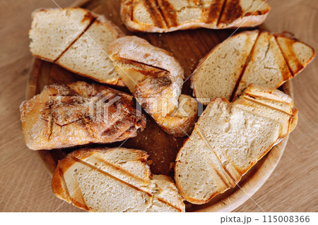 dried wheat bread, croutons, pieces, on a wooden round board 115008366
