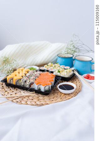 Sushi delivery. Set of rolls in a disposable box on a black background. Top view Sushi delivery. Set of rolls in a disposable box on a black background. Top view 115009160