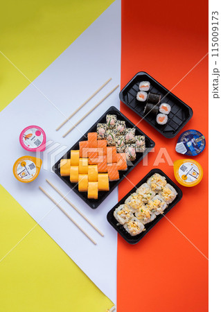 Sushi delivery. Set of rolls in a disposable box on a black background. Top view 115009173
