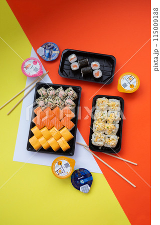 Sushi delivery. Set of rolls in a disposable box on a black background. Top view Sushi delivery. Set of rolls in a disposable box on a black background. Top view 115009188