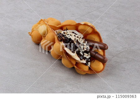 Trendy Hong Kong bubble waffles with ice cream, cream and berries on white wooden background. Copy space Trendy Hong Kong bubble waffles with ice cream, cream and berries on white wooden background. Copy space 115009363