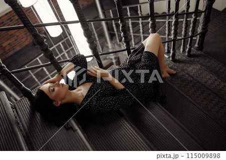 A woman in a black dress is laying on a staircase A woman in a black dress is laying on a staircase 115009898