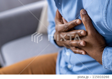 Closeup of person clutching their chest, indicating possible heart pain or stress. Seek immediate medical attention for such symptoms to address health concerns and emergencies 115010260