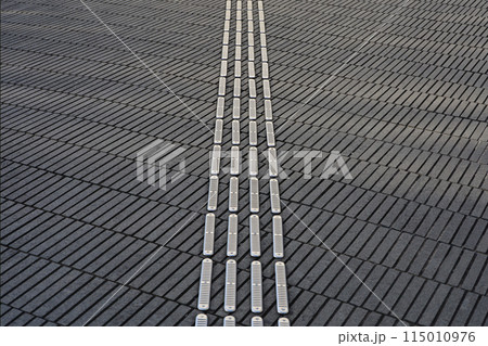 歩道に設置された視覚障害者誘導用ブロックにクローズアップした背景素材用写真 115010976