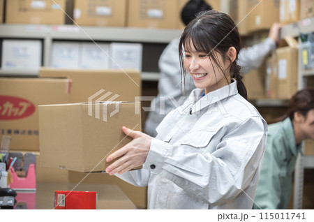 梱包作業する作業着姿の若い女性 115011741