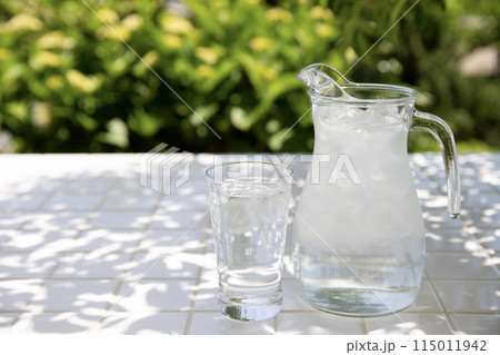 冷たい水、庭の木陰のテーブルにピッチャーとグラス 115011942