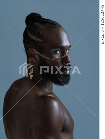 Serious black shirtless gay man with bright makeup Serious black shirtless gay man with bright makeup 115012445
