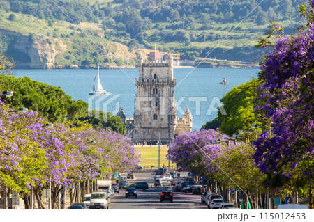 Belem Tower, Jacaranda Blooming Purple Blue Trees and Sailing Boat on Sunny Day. Lisbon, Portugal Belem Tower, Jacaranda Blooming Purple Blue Trees and Sailing Boat on Sunny Day. Lisbon, Portugal 115012453